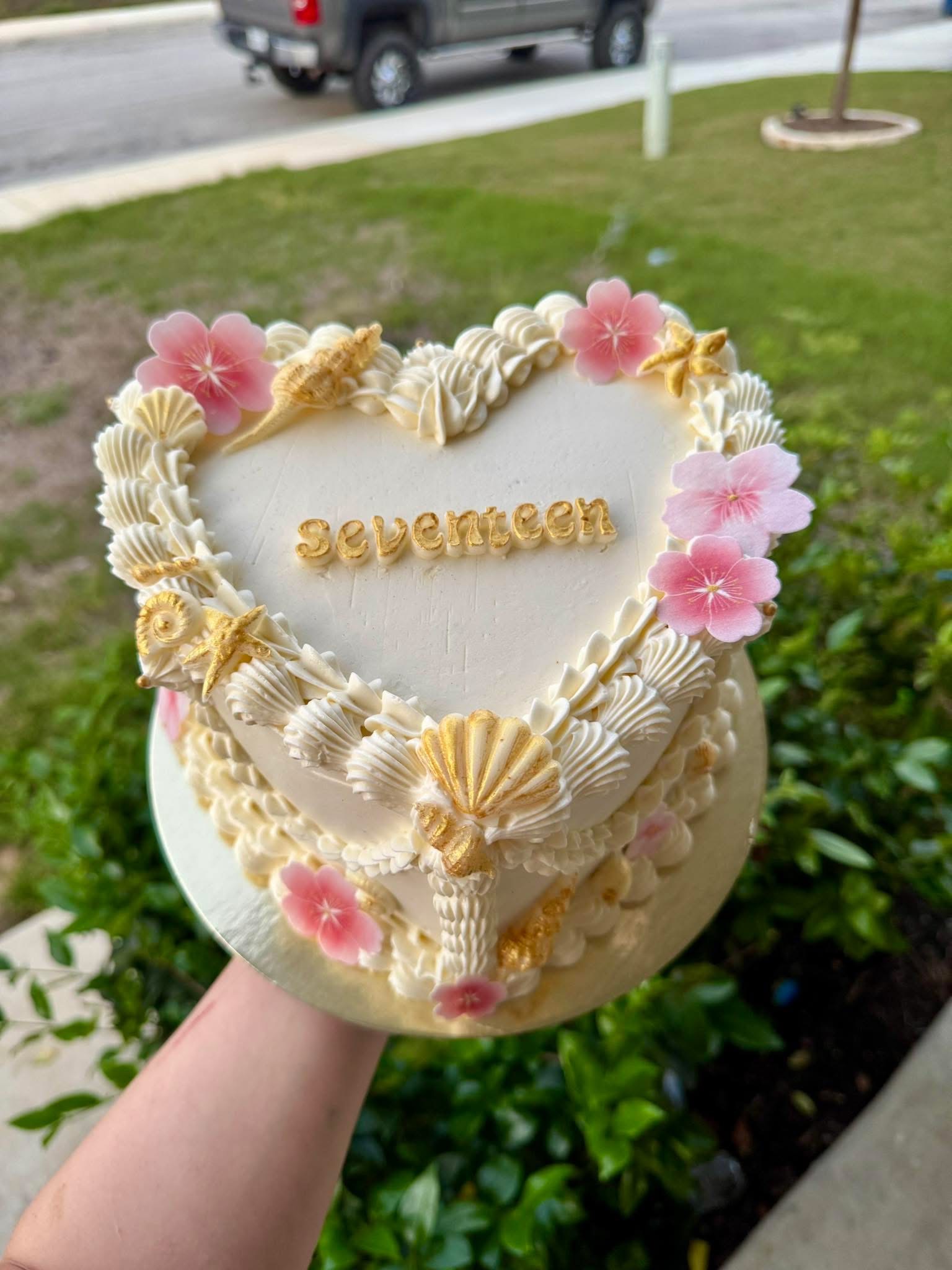 Heart-shaped cake with pink flowers and gold details